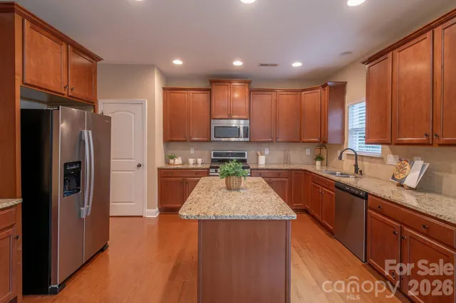 a kitchen with granite countertop stainless steel appliances a refrigerator sink stove microwave and cabinets