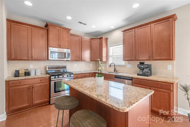 a kitchen with kitchen island granite countertop a sink stove and cabinets