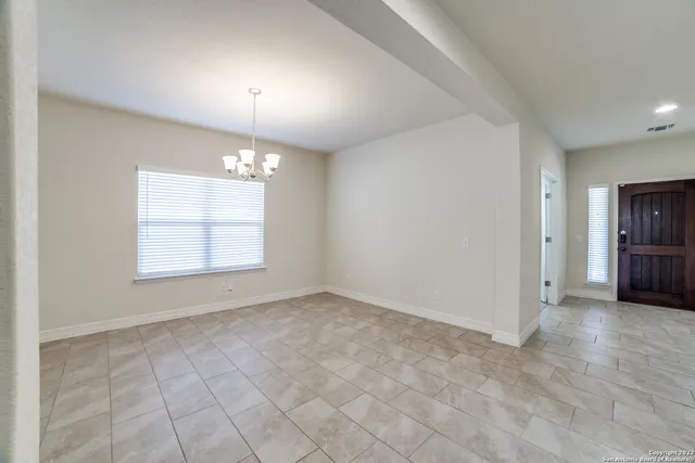 an empty room with chandelier and windows