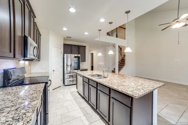 a kitchen with granite countertop kitchen island stainless steel appliances a sink stove and oven