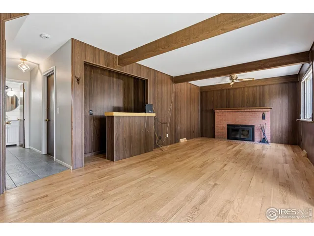 a view of an empty room with wooden floor and a fireplace