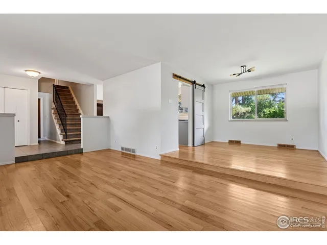 a view of empty room with window and wooden floor