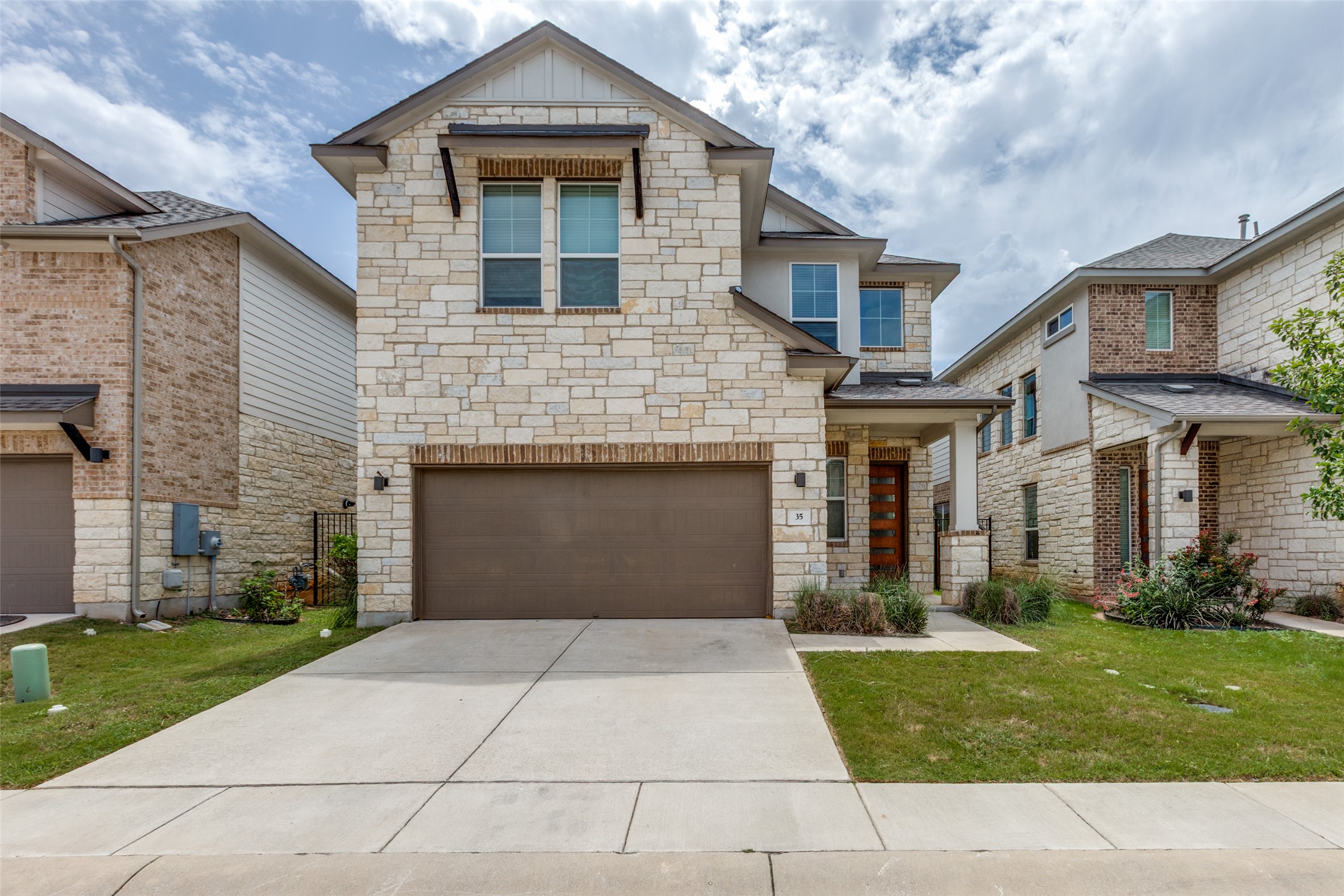 900 Old Mill Road, Unit 35 Cedar Park, TX 78613 - Photo 1 of 1 Craftsman-style house with stone siding, an attached garage, a front yard, concrete driveway, and board and batten siding