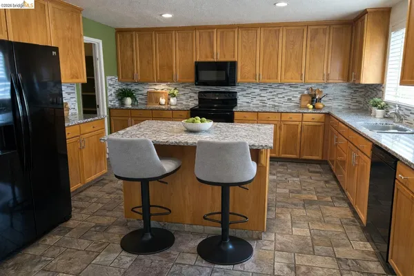 a kitchen with stainless steel appliances a stove a sink a microwave a refrigerator and cabinets