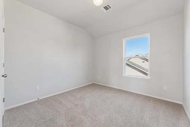 a view of an empty room with a window and a kitchen