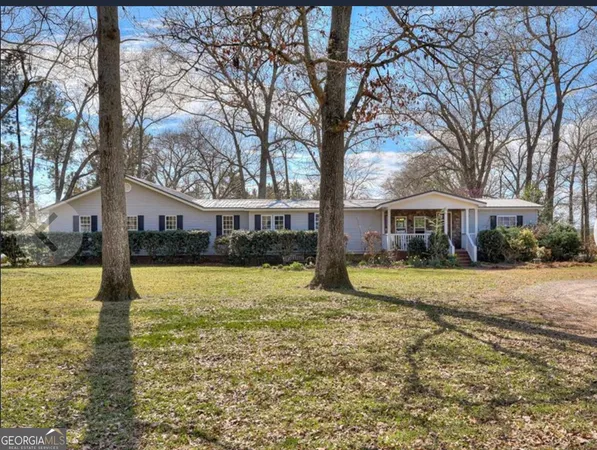a front view of a house with a yard and large trees