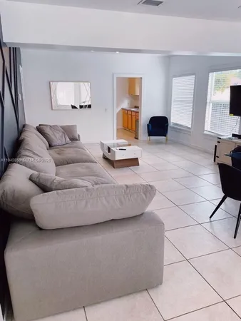 a living room with couches and kitchen view