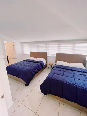 a bedroom with two beds and a lamp on dresser