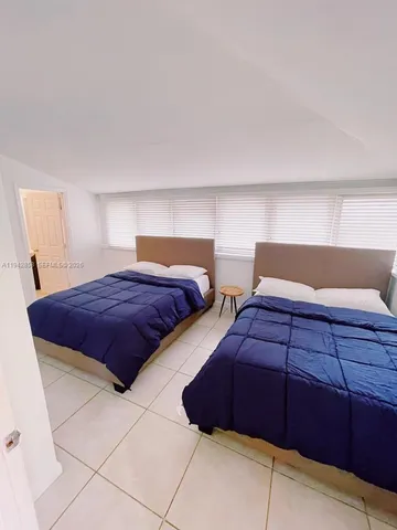 a bedroom with two beds and a lamp on dresser