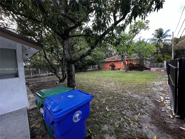 a view of a backyard with table and chairs a fire pit and a large tree