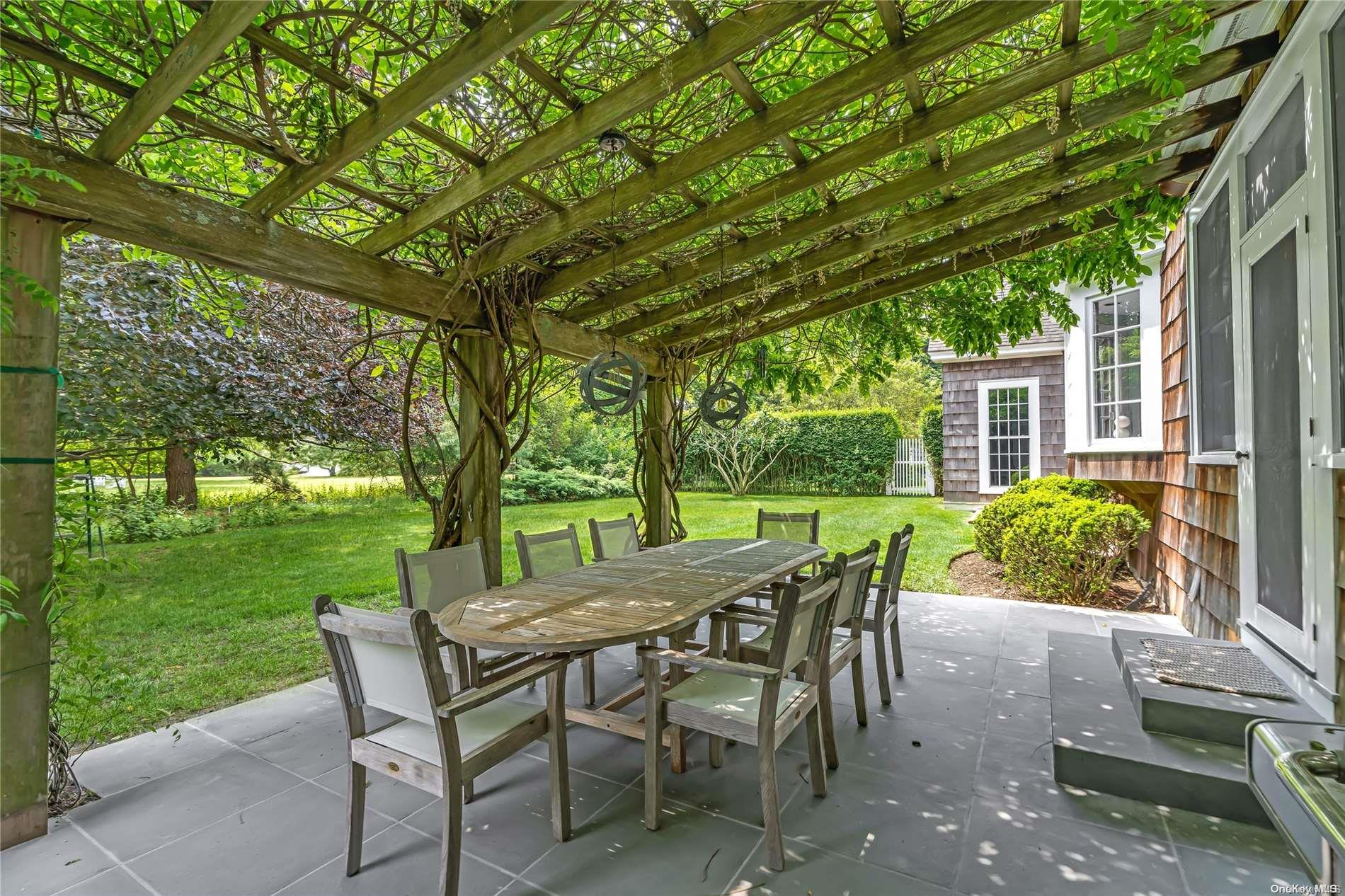 5 Shinnecock Road Quogue, NY 11959 - Photo 16 of 35 a view of a patio with a table chairs and a backyard