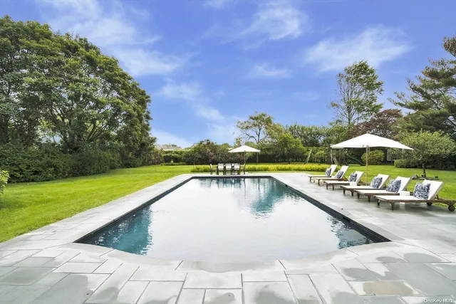 a view of swimming pool with outdoor seating and trees in the background