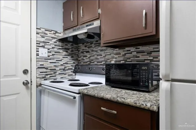 a kitchen with granite countertop a stove sink and microwave