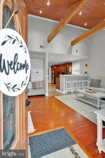 a view of a kitchen with kitchen island a stove a wooden floor and a living room view