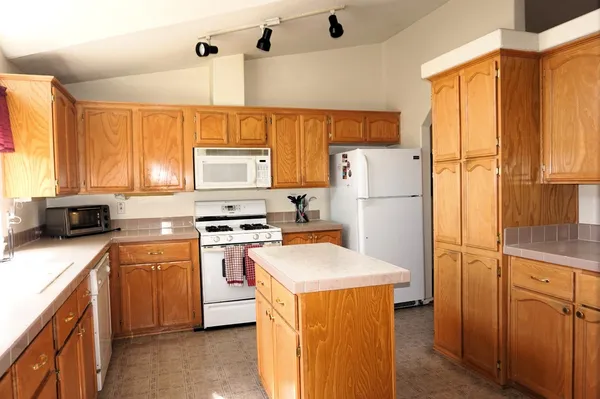 a kitchen with a refrigerator a stove a sink dishwasher and wooden cabinets