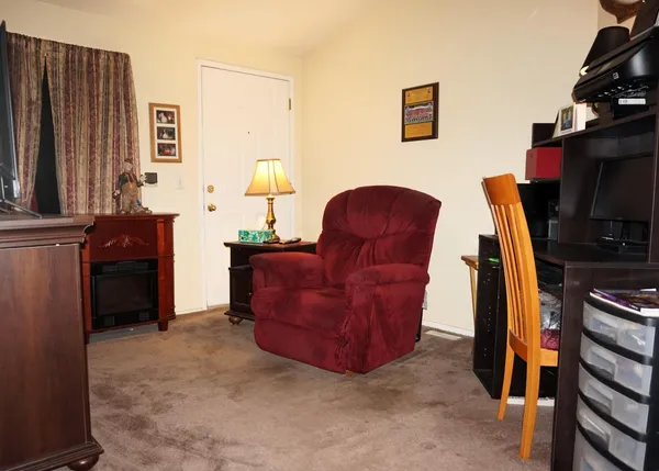 a living room with furniture a flat screen tv and a refrigerator