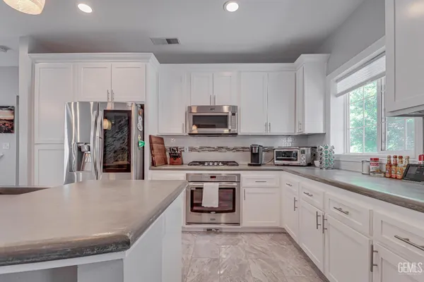 a kitchen with stainless steel appliances granite countertop a stove a sink dishwasher a refrigerator and a microwave