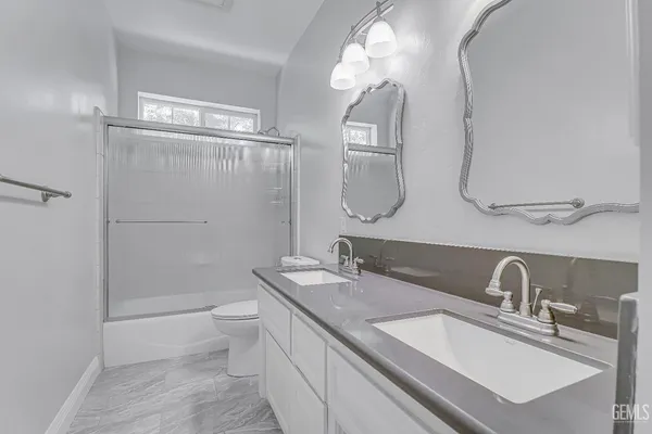 a bathroom with a double vanity sink toilet and shower