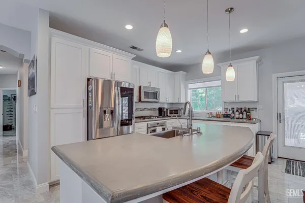 a kitchen with stainless steel appliances a refrigerator a stove a sink a dining table and chairs