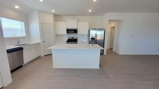 a large kitchen with stainless steel appliances a sink a stove a chimney a refrigerator and cabinets