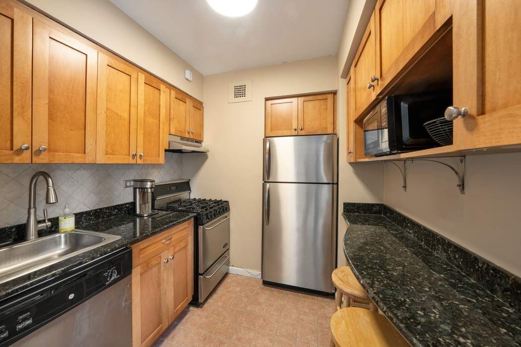 305 East 72nd Street, Unit 5AS Manhattan, NY 10021 - Photo 5 of 11 a kitchen with stainless steel appliances granite countertop a refrigerator a stove and a sink