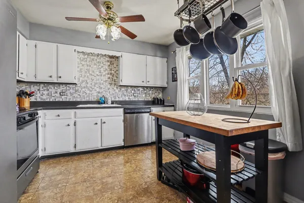 a kitchen with stainless steel appliances granite countertop a sink a stove and a wooden cabinets