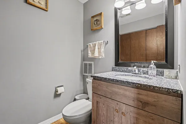 a bathroom with a granite countertop sink toilet and mirror