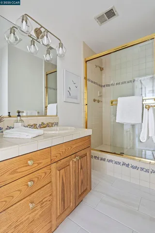 a bathroom with a granite countertop sink a mirror and shower