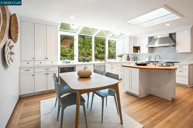 a kitchen with stainless steel appliances a table chairs sink and cabinets