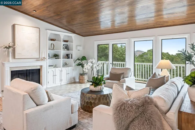 a living room with furniture large windows and wooden floor