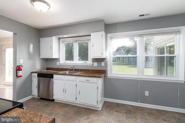 a kitchen with granite countertop a stove a sink dishwasher and wooden cabinets