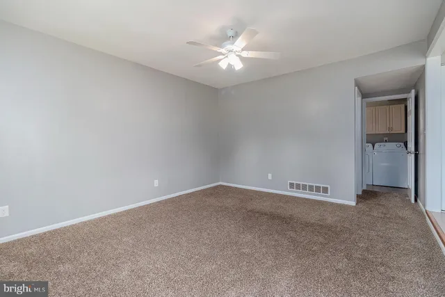 an empty room with closet and a ceiling fan