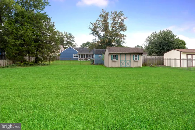 a house that is sitting in the grass with large trees