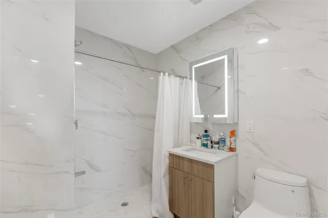 a bathroom with a sink toilet vanity and shower