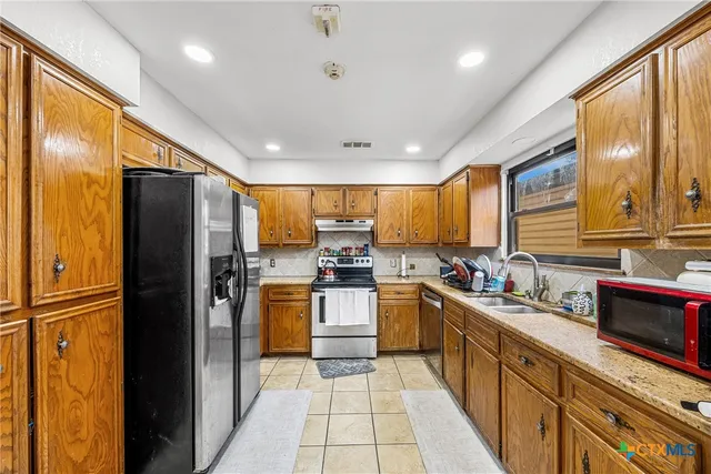 a kitchen with stainless steel appliances granite countertop refrigerator a sink a stove top oven and a refrigerator
