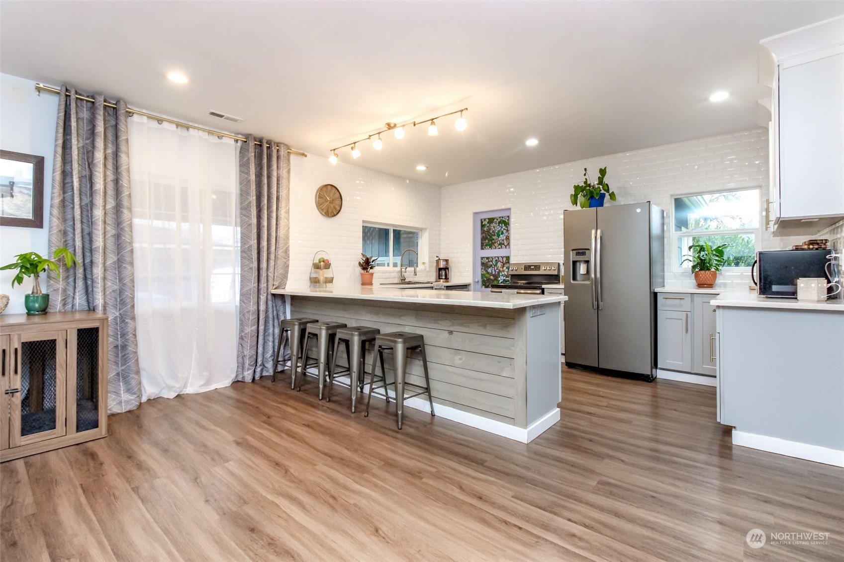 3903 Freeman Road East Edgewood, WA 98371 - Photo 13 of 40 a kitchen with stainless steel appliances kitchen island granite countertop a refrigerator a stove a sink and a dining table with wooden floor
