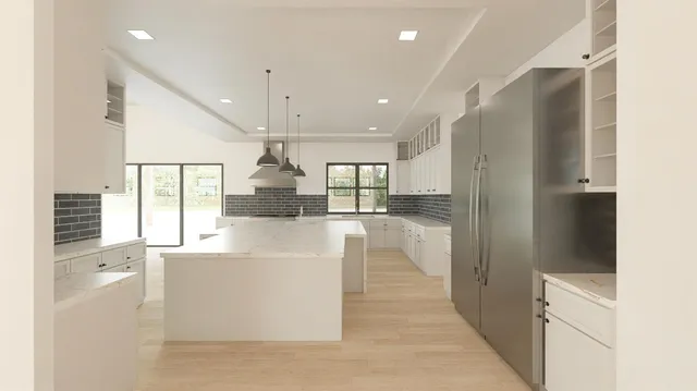 a large white kitchen with stainless steel appliances kitchen island a large counter top and a refrigerator