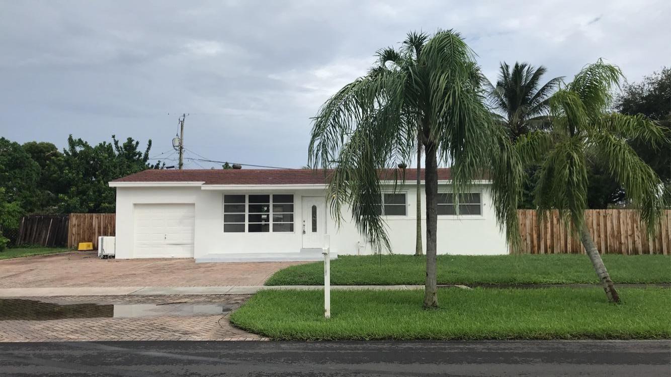 a white house with a small yard and palm trees
