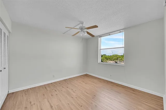 an empty room with wooden floor and ceiling fan