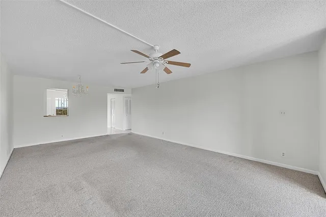 an empty room with a ceiling fan and window