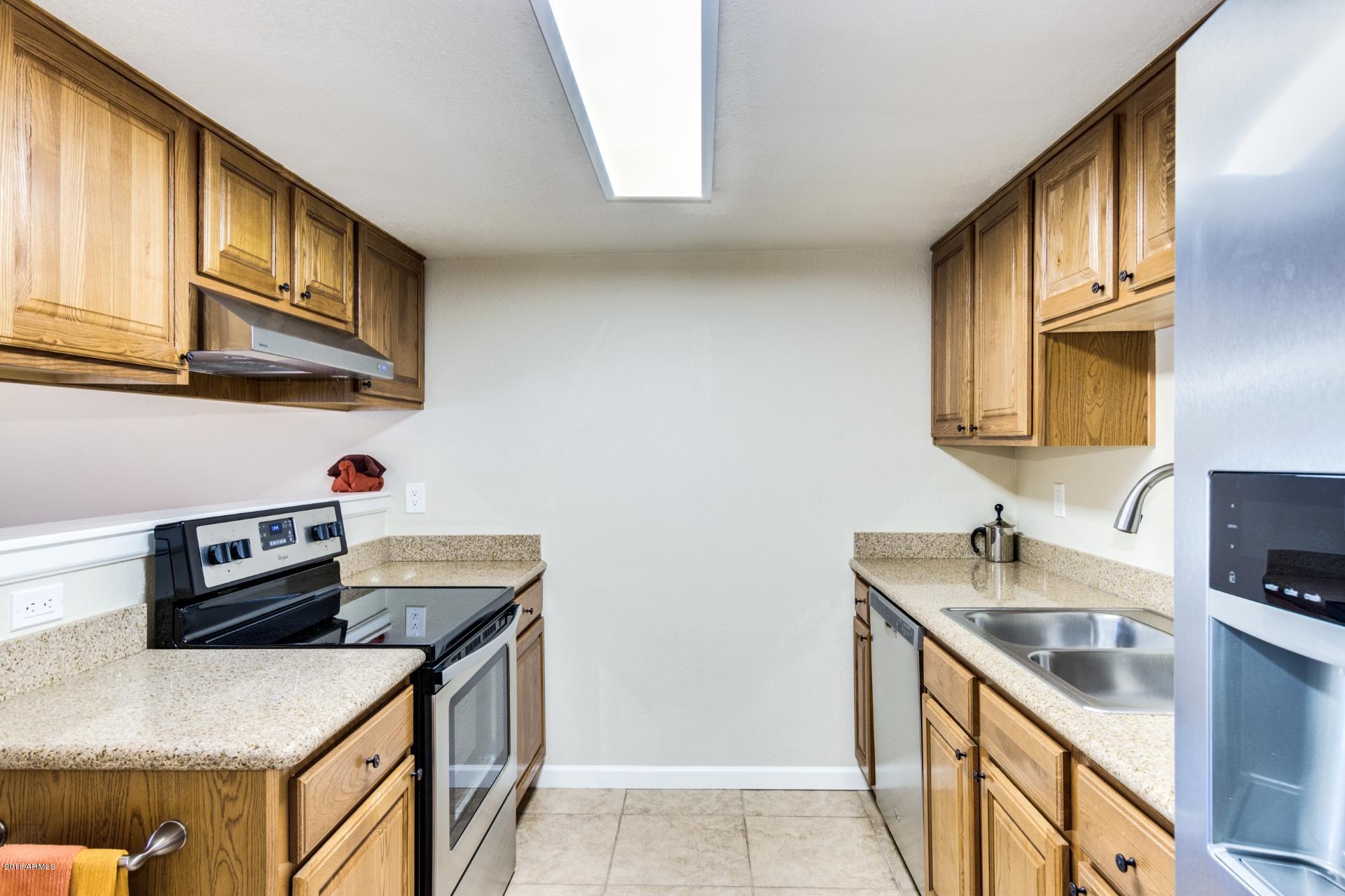 3511 East Baseline Road, Unit 1082 Phoenix, AZ 85042 - Photo 9 of 23 a kitchen with stainless steel appliances granite countertop a sink stove and cabinets