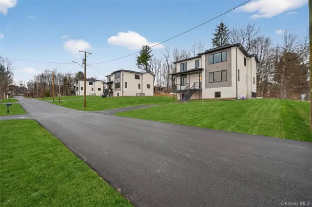 a view of a white house with a big yard and large trees