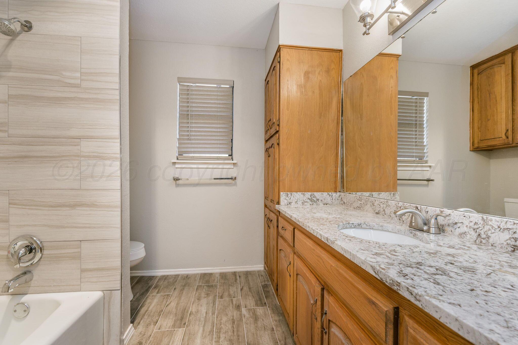 6000 Hampton Drive Amarillo, TX 79109 - Photo 15 of 19 a bathroom with a granite countertop sink and a bathtub