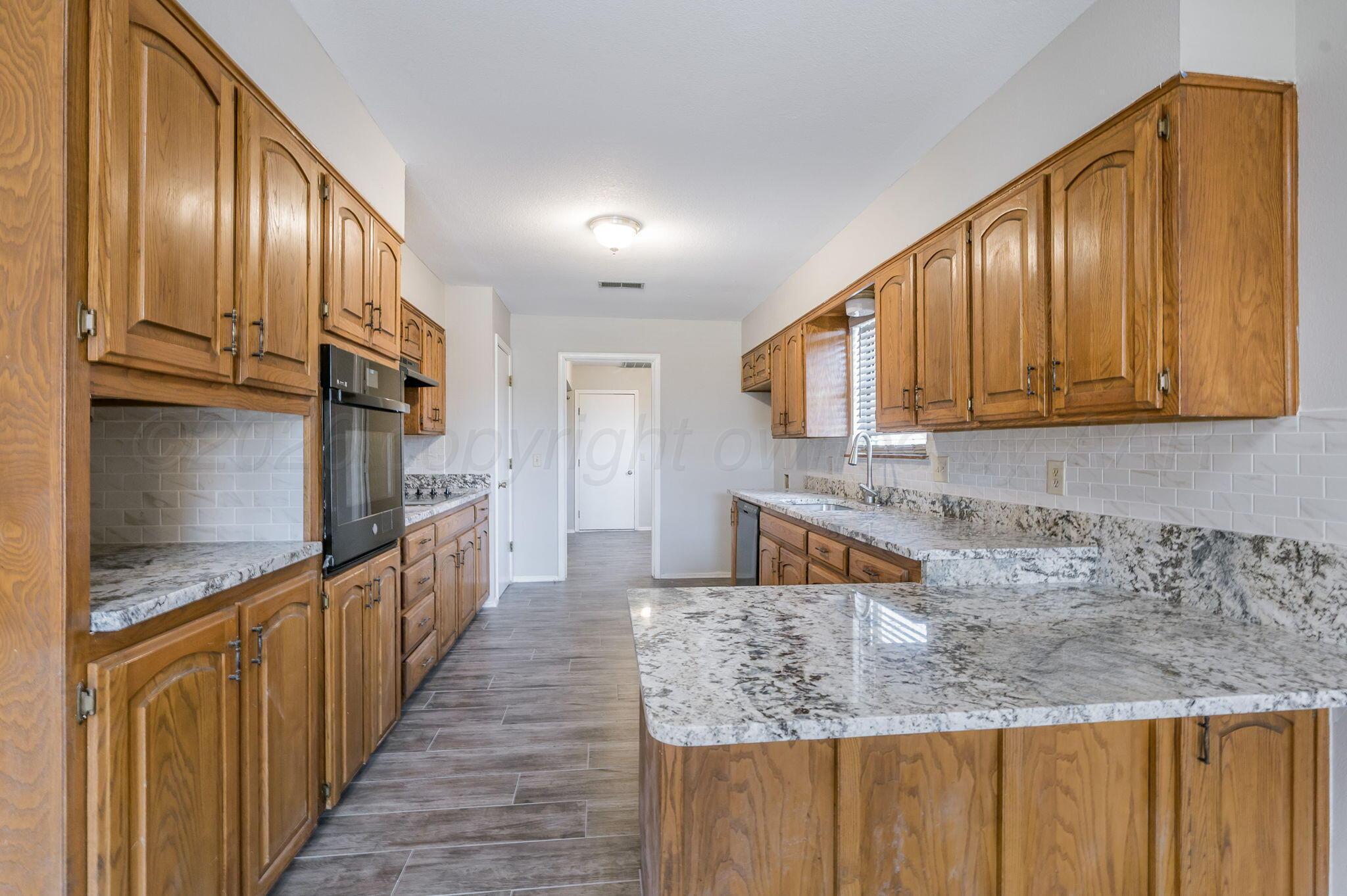 6000 Hampton Drive Amarillo, TX 79109 - Photo 6 of 19 a kitchen with stainless steel appliances granite countertop wooden cabinets a granite counter tops and a view of living room