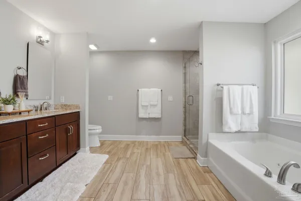 a spacious bathroom with a tub sink and mirror