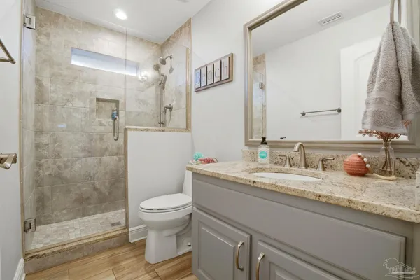 a bathroom with a granite countertop sink a toilet and a mirror