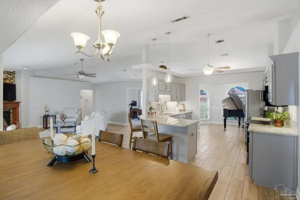 a living room with furniture a chandelier and a dining table with wooden floor