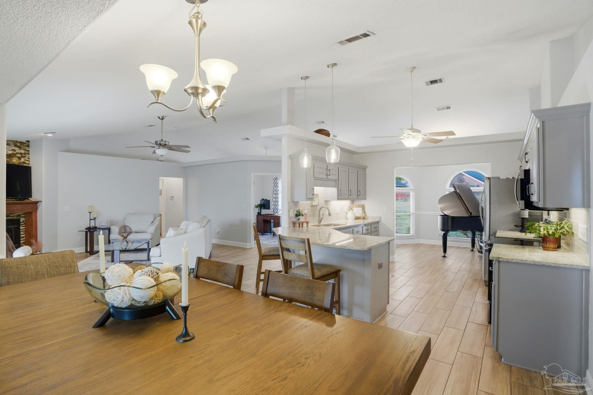 4249 Spindlewick Drive Pace, FL 32571 - Photo 7 of 26 a living room with furniture a chandelier and a dining table with wooden floor