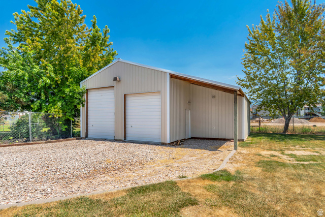4752 South 4075th Street West Roy, UT 84067 - Photo 2 of 28 Detached metal garage with two roll-up doors, an extended carport, and a gravel driveway