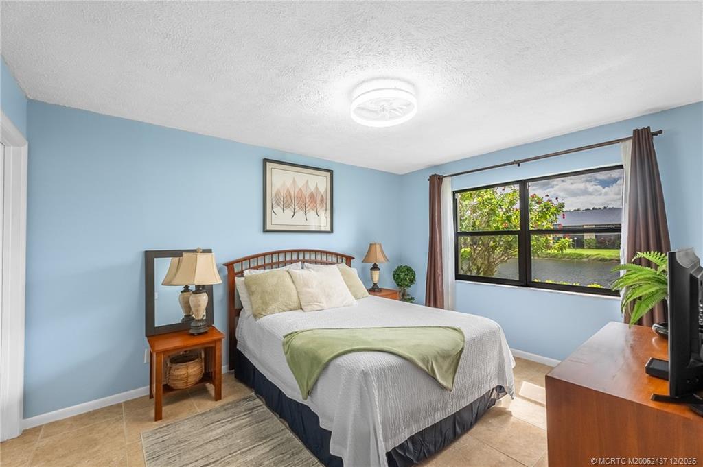 3171 Southeast Aster Lane, Unit 1103 Stuart, FL 34994 - Photo 8 of 26 a bedroom with a large bed and a window